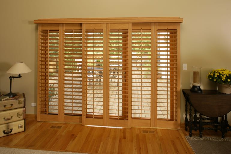 plantation shutters on sliding door leading to outdoor porch.